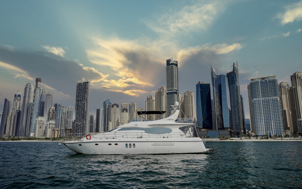 Luxury yacht Mayyas sailing at sunset with Dubai skyscrapers